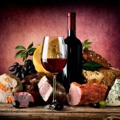 Pahar de vin roșu lângă o sticlă, în lumină caldă